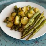 Delicious roasted potatoes and asparagus served on a white plate.