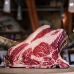 High-quality marbled beef rib displayed on a rustic wooden table, showcasing its raw texture and rich colors.